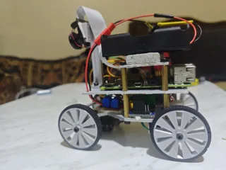 Fotografía de The Red Castle de su coche robot completo visto de lado, con cuatro ruedas grises, cámara elevada y chasis de varios niveles.