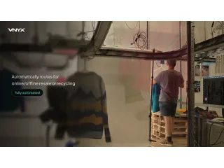 Fotograma de la línea VNYX100 en funcionamiento, con una prenda suspendida en el transportador y un operario al fondo.