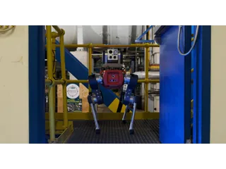 El robot cuadrúpedo ANYmal frente a una puerta azul abierta en una instalación industrial, en una fotografía oficial del piloto de Whitegate.