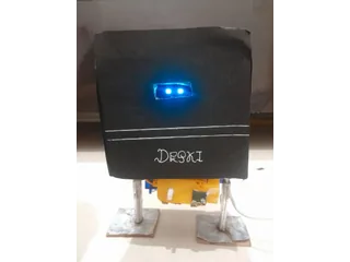 Fotografía de CraftyMind1020 de Deski V1 completo, con carcasa negra artesanal, ojos OLED azules, dos patas y pies planos.