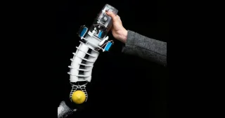 Bionic Handling Assistant completo, sostenido con una mano y sujetando una pelota junto a la trompa de un elefante.