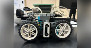 Fotografía de Teikyo RoboLet’sGo de su coche robot completo visto de lado, con piezas LEGO, cuatro ruedas y electrónica sobre el chasis.