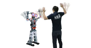 Meccanoid G15KS completo junto a una persona que realiza un gesto con los brazos, en una fotografía promocional de Takara Tomy.