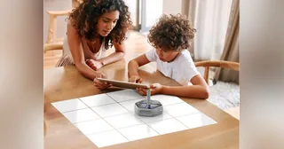 Dos niños programan un Root RT0 con un rotulador sobre una cuadrícula