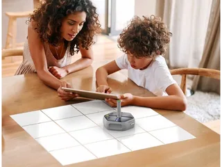 Dos niños programan un Root RT0 con un rotulador sobre una cuadrícula