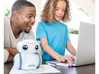 Fotografía oficial de un adulto y una niña junto a Artie 3000, que está sobre un dibujo verde, mientras ella utiliza un ordenador portátil.