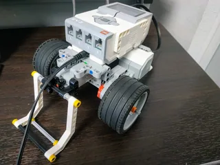 Robot LEGO EV3 de ruedas con una pinza frontal sobre una mesa.
