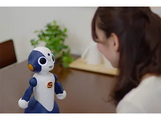 Sota azul y blanco sobre una mesa, con brazos levantados ante una persona.