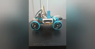Fotografía de RoboTronics Bilbao de su coche robot completo visto de lado, con piezas claras y azules, cuatro ruedas y sensores visibles.