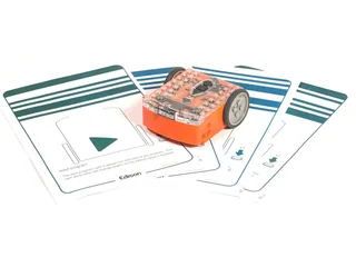 Fotografía oficial de Edison V3, con carcasa naranja y cubierta transparente, sobre tarjetas de programación con códigos de barras.