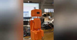 Fotografía del equipo Posture Pet del robot completo, con cuerpo de bloques naranjas, articulaciones y cara OLED.