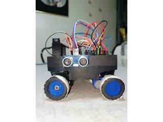Fotografía de Vitality de su coche robot completo, con cuatro ruedas azules, electrónica visible y sensor ultrasónico lateral.