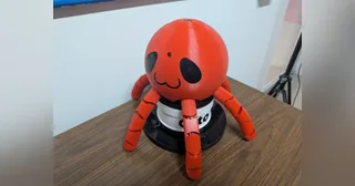 Fotografía de Daniel Peña Cruz de Otto completo, con cuerpo de pulpo rojo y base giratoria negra sobre una mesa.
