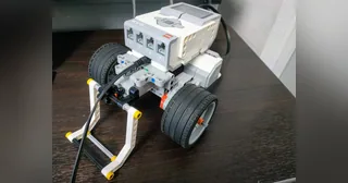Robot LEGO EV3 de ruedas con una pinza frontal sobre una mesa.