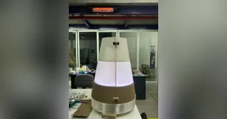 Fotografía de Nicolas Lara del robot completo, con cuerpo de madera y cubierta translúcida iluminada sobre su base móvil.