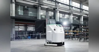 Carretilla autónoma Stäubli FL1500 blanca y negra en una nave industrial, vista desde delante y un lateral.