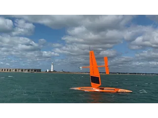 Saildrone Explorer naranja identificado como SD 1021 navegando por el mar con su vela rígida.