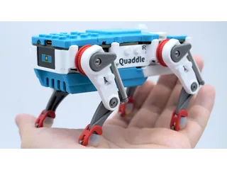 Fotografía de un Petoi Quaddle azul y blanco sobre la palma de una mano, con los mecanismos de sus patas visibles; miniatura del vídeo oficial.