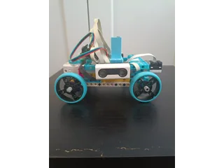 Fotografía de RoboTronics Bilbao de su coche robot completo visto de lado, con piezas claras y azules, cuatro ruedas y sensores visibles.