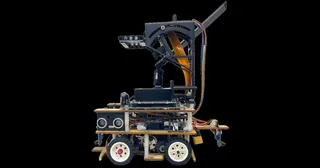 Fotografía de Fire On All Cylinders de su robot completo visto de lado, con plataformas de madera, ruedas claras y soporte elevado de percepción.