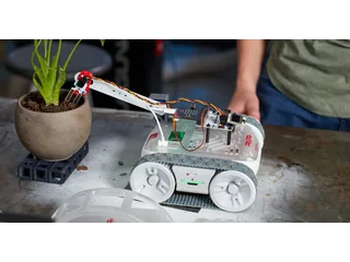 Fotografía oficial de un Sphero RVR+ con una micro:bit y ampliaciones montadas sobre el chasis, junto a una maceta.