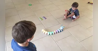 Code-a-pillar completo con varios segmentos conectados sobre un suelo de baldosas durante una actividad con niños.
