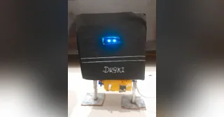 Fotografía de CraftyMind1020 de Deski V1 completo, con carcasa negra artesanal, ojos OLED azules, dos patas y pies planos.