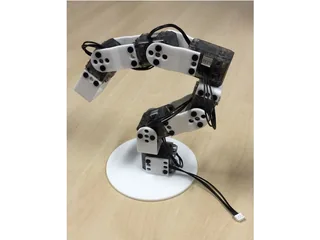 Brazo Poppy Ergo Jr con piezas blancas impresas en 3D y motores transparentes sobre una mesa de madera