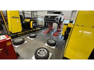 Fotografía del sistema amarillo PitPro a ambos lados de un coche elevado en un taller, con cuatro ruedas preparadas.