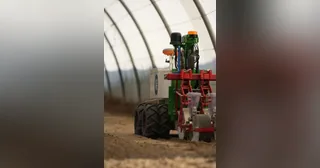 Robot Naïo Oz con un apero en un invernadero.