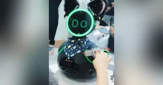 Fotografía recortada de una publicación de INDEMIND de Donutbot negro completo en una demostración de interacción en feria.