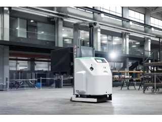 Carretilla autónoma Stäubli FL1500 blanca y negra en una nave industrial, vista desde delante y un lateral.