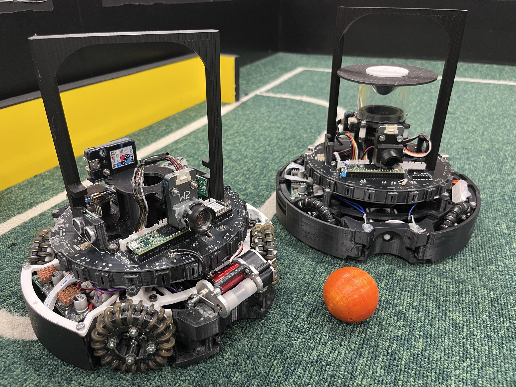 Fotografía del equipo AIR de dos ejemplares completos de su robot de fútbol de 2026, con ruedas omnidireccionales y sensores.
