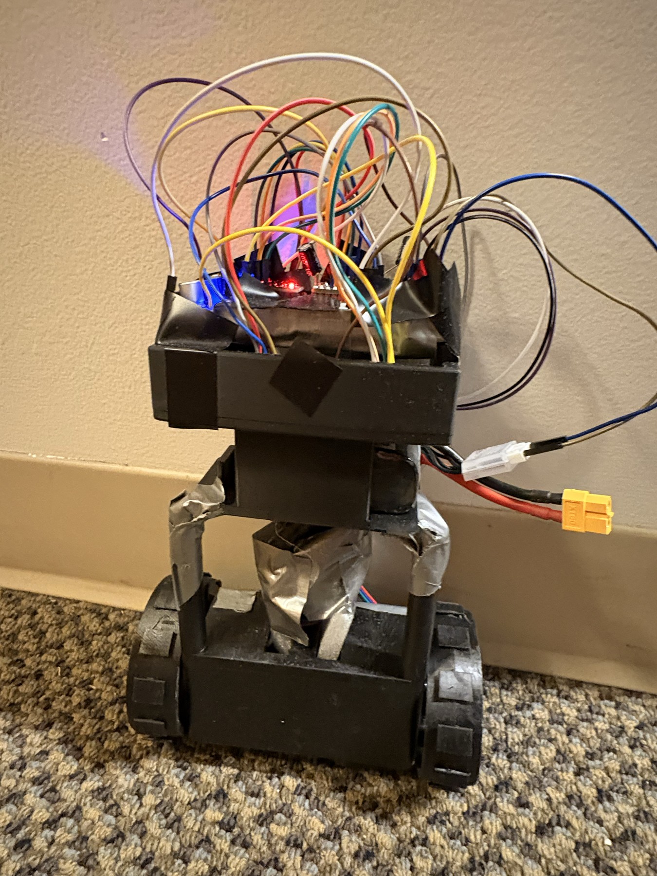 Fotografía de Amadeu Behrend del robot de equilibrio completo, con estructura negra vertical, dos ruedas y Raspberry Pi visible.