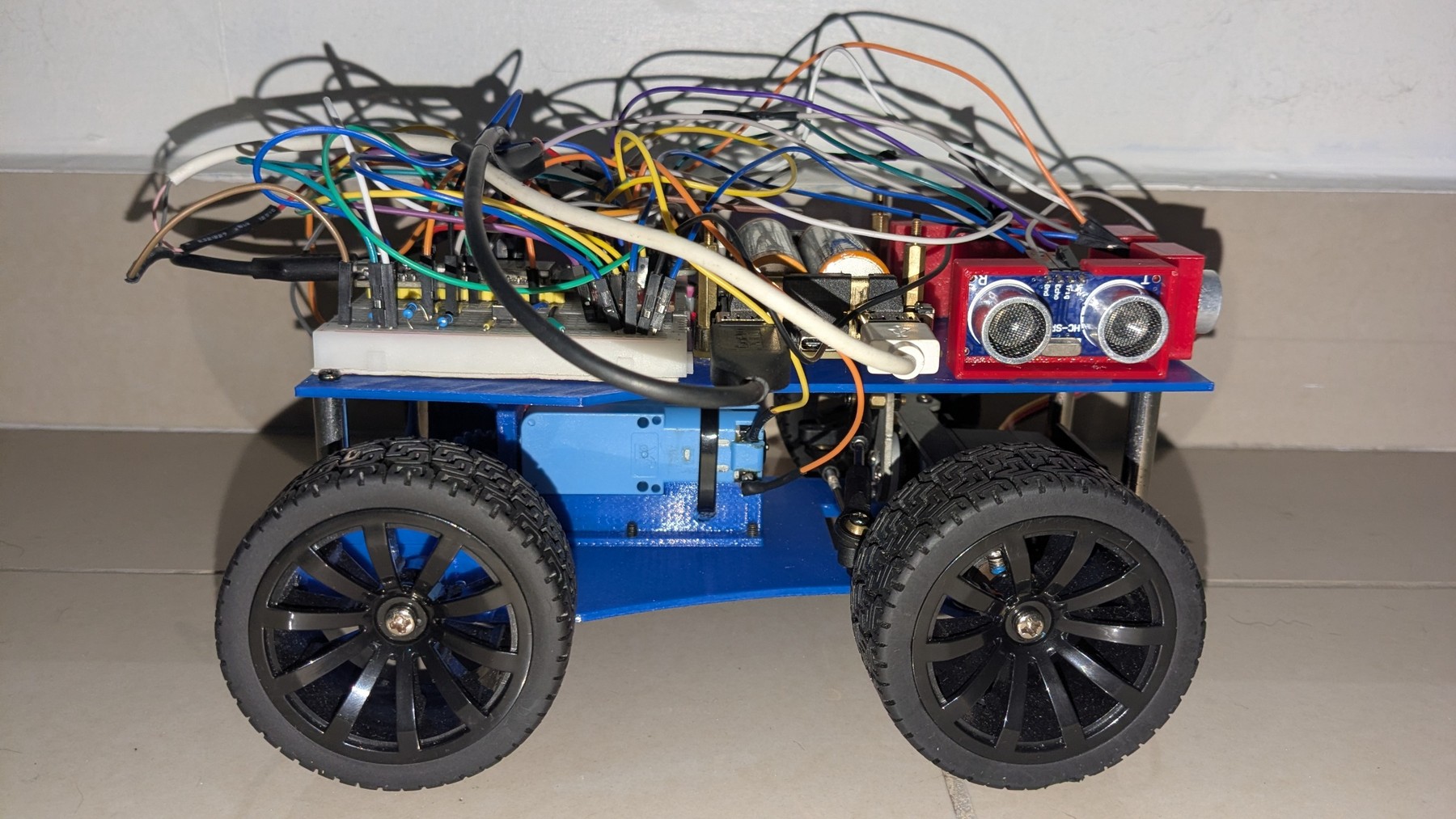 Fotografía de Encore V2 de su coche robot completo visto de lado, con estructura azul, cuatro ruedas y ultrasonidos.