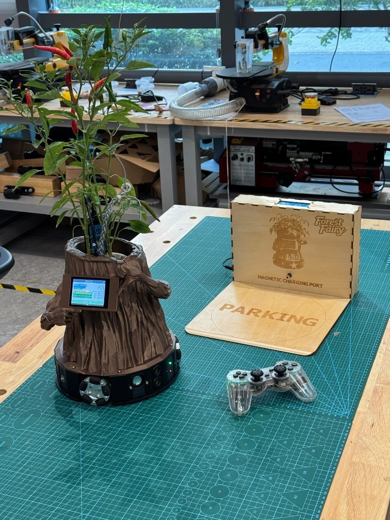 Fotografía de Hongfeng Yu de Forest Fairy completo, con una planta de chile, pantalla frontal y base de tres ruedas, junto a su estación y mando.