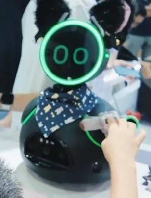 Fotografía recortada de una publicación de INDEMIND de Donutbot negro completo en una demostración de interacción en feria.