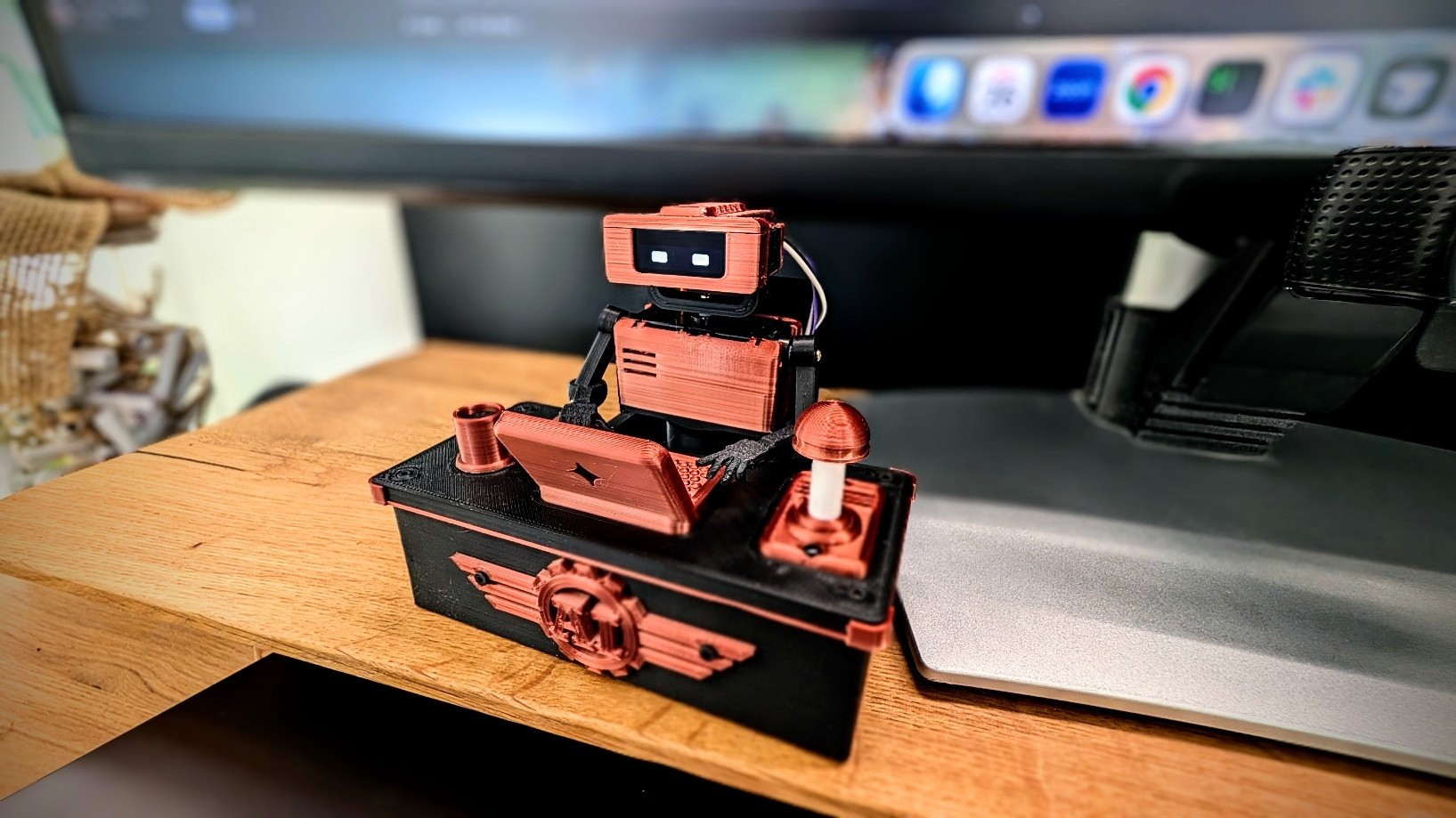 Fotografía oficial del montaje completo de Tiny Engineer, con cuerpo naranja, mesa propia y campana, sobre un escritorio.