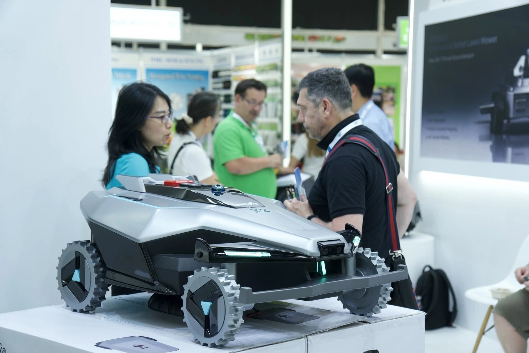 Fotografía oficial del prototipo Lawnova X2 completo expuesto en spoga+gafa 2026, con visitantes del stand al fondo.