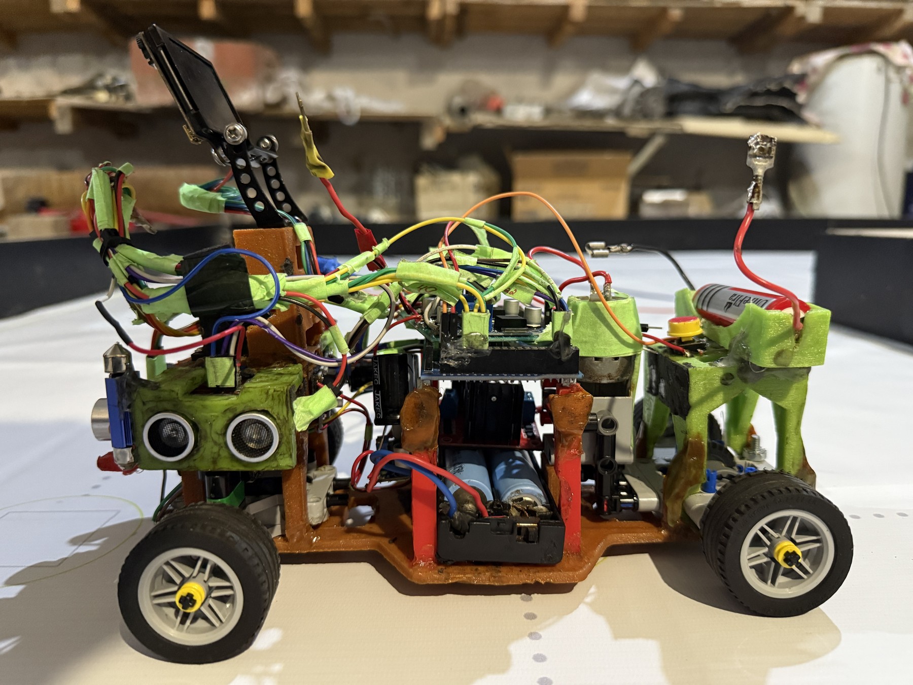 Fotografía del Team NEDrobotics de su coche robot completo, con piezas impresas verdes, ruedas negras, ultrasonidos y electrónica visible.