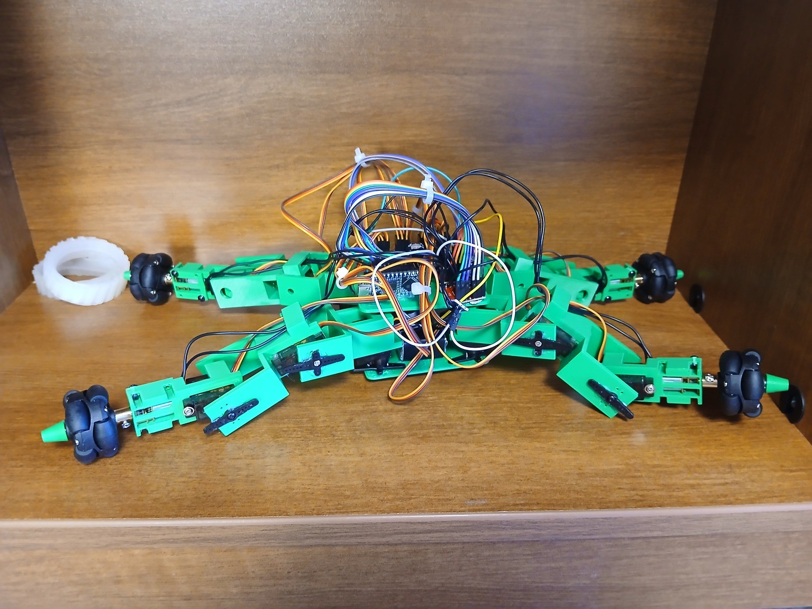 Fotografía de OriginalGoodUsername del robot híbrido completo, con cuerpo verde, cuatro patas articuladas y ruedas en los extremos.