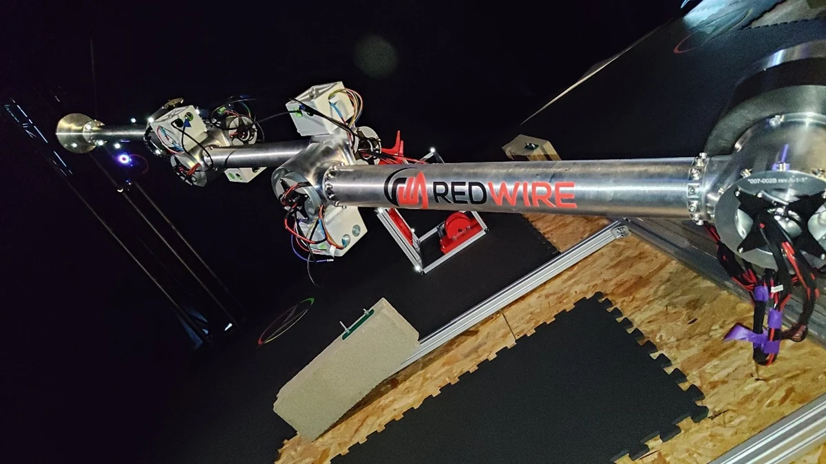Prototipo del brazo espacial Manus de Redwire, con estructura metálica y cableado, extendido durante una prueba en laboratorio.