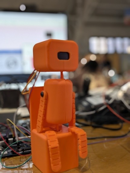 Fotografía del equipo Posture Pet del robot completo, con cuerpo de bloques naranjas, articulaciones y cara OLED.