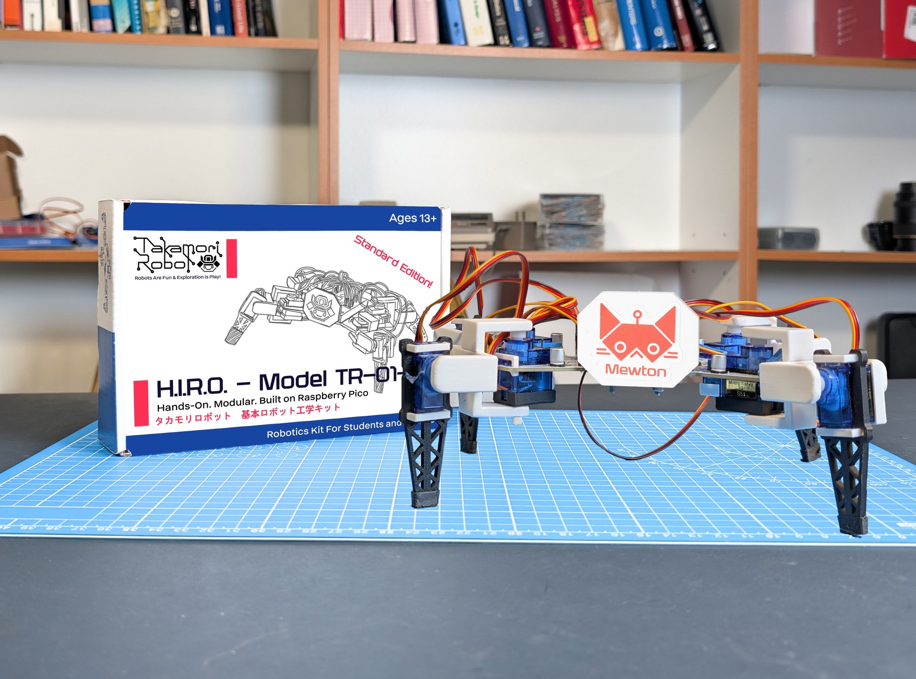 Fotografía oficial de H.I.R.O. TR-01-A completo, con cuatro patas y cuerpo blanco, sobre una mesa de montaje con la caja del kit.