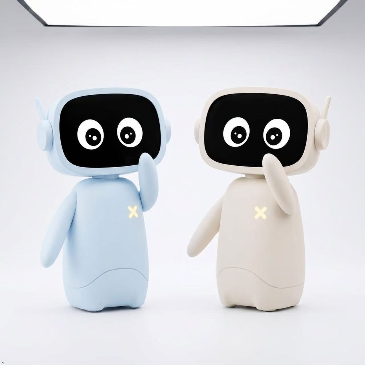 Dos robots físicos XiaoMu en azul y crema sobre un escritorio